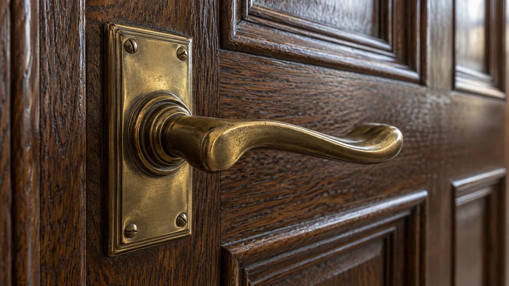 Close-up of aged brass ironmongery against richly grained oak